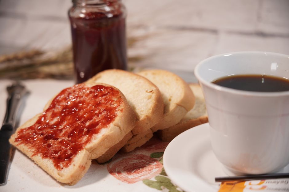 Mesa de madera con baguette, frascos de mermelada y frutos rojos frescos